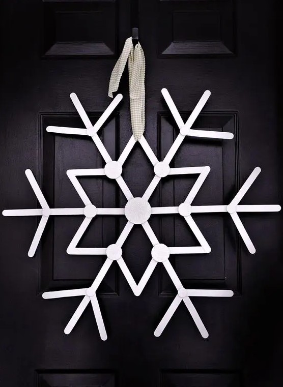 an oversized white snowflake Christmas wreath is a creative idea that will make your front door stand out a lot