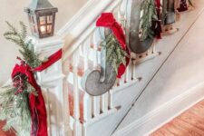 51 rustic railing decor with metal letters, evergreens, lights and red ribbons, some evergreens with berries and a candle lantern for Christmas