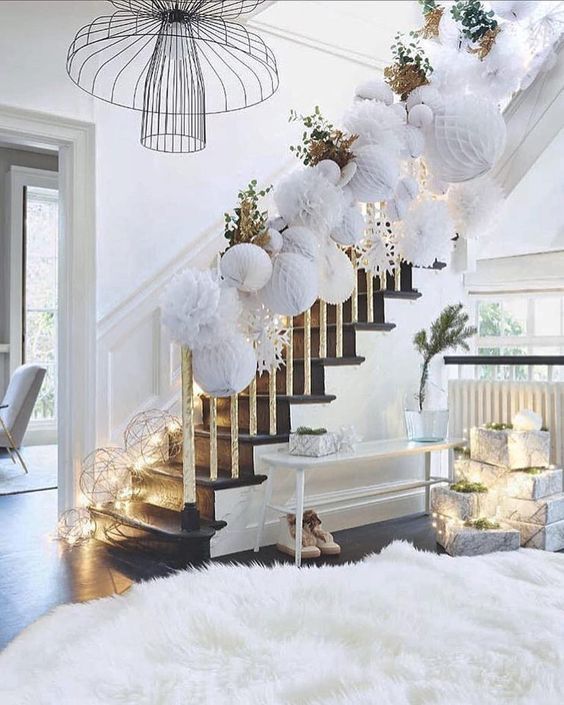 usual and gilded leaves paired with white paper pompoms are an amazing idea for Christmas banister decor, add lights to the steps