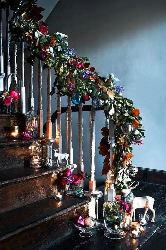 a fantastic Christmas decoration of faux leaves and flowers with colorful baubles and matching arrangements right on the stairs for those who love color