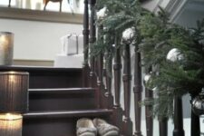 58 a super lush evergreen garland with large mercury glass ornaments and some candle lanterns in crochet cozies on the stairs for Christmas