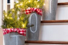 61 metal buckets with evergreens and lights decorated with red checked ribbons placed on the stairs will give them a rustic feel