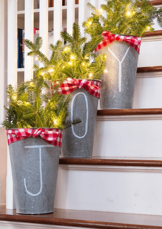 metal buckets with evergreens and lights decorated with red checked ribbons placed on the stairs will give them a rustic feel