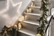 62 pillar candles right on the steps, light stars and an evergreen garland on the banister are a lovely Christmas combo