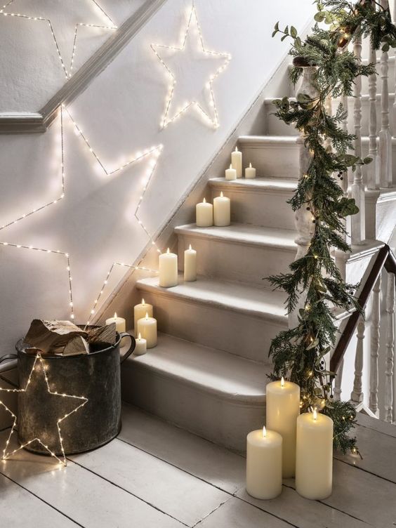 pillar candles right on the steps, light stars and an evergreen garland on the banister are a lovely Christmas combo