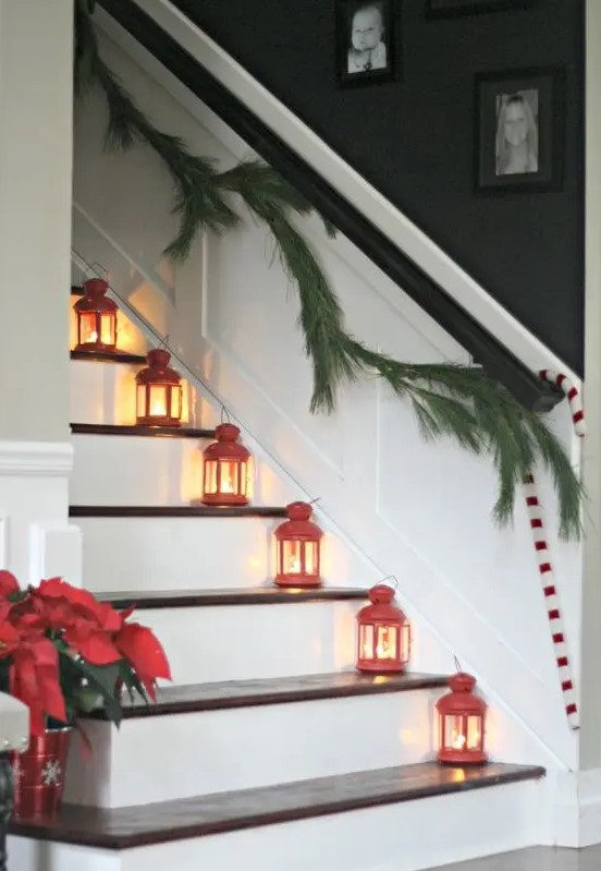 red lanterns placed on the stairs and an evergreen garland are a lovely and classic combo for the holidays