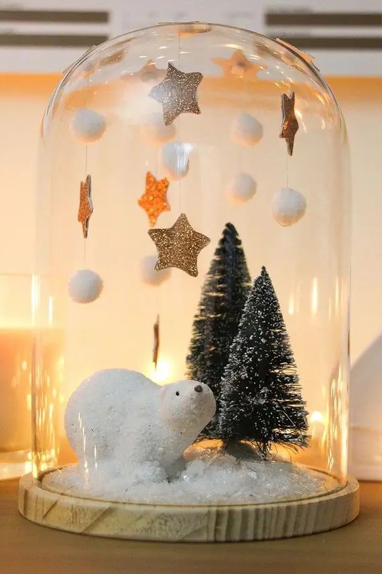 a Christmas terrarium with faux snow, a polar bear, bottle brush Christmas trees, pompoms and glitter stars