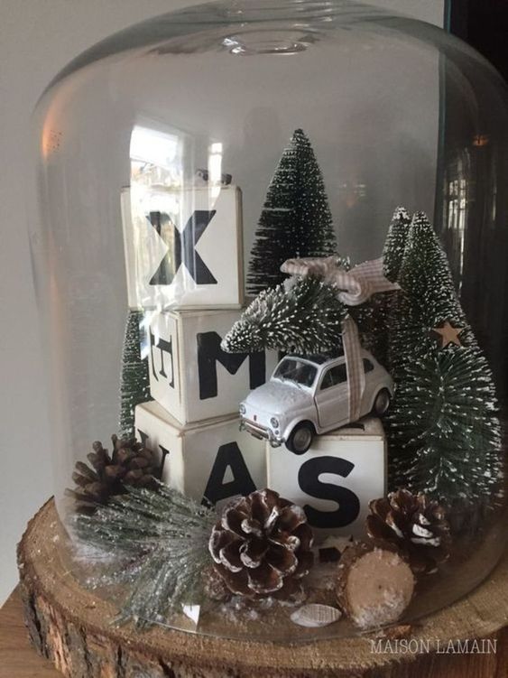 a Christmas terrarium with pinecones, evergreens, cubes, a car carrying a tree and some bottle brush trees
