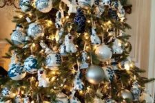a Christmas tree decorated with lights, blue and white plus silver ornaments, ribbons and porcelain pieces is lovely