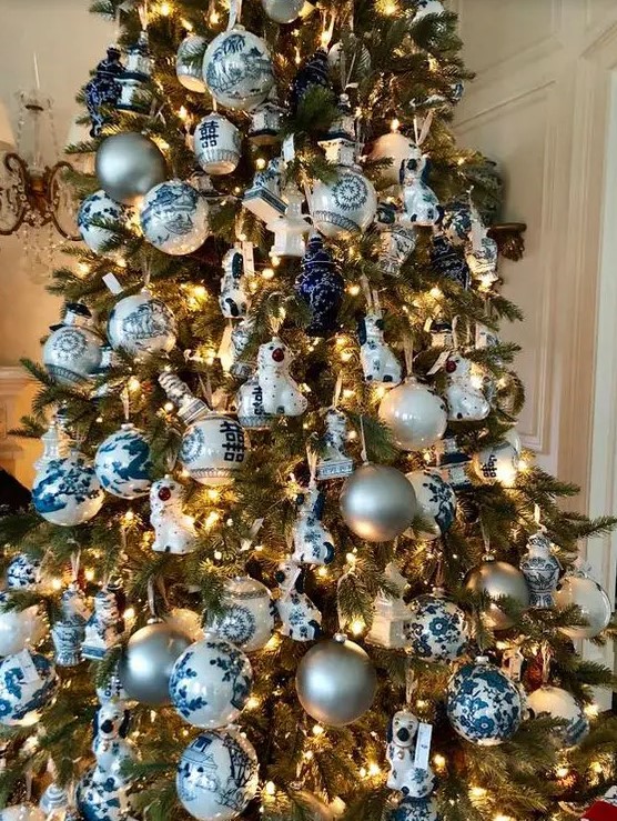 a Christmas tree decorated with lights, blue and white plus silver ornaments, ribbons and porcelain pieces is lovely