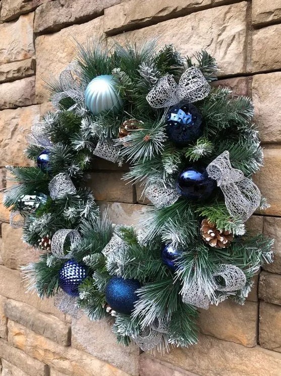 a Christmas wreath with bold blue and light blue ornaments, pinecones and silver ribbons is a lovely and chic idea