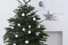 a Scandinavian Christmas tree with silver and white ornaments placed into a basket is a stylish and cozy idea