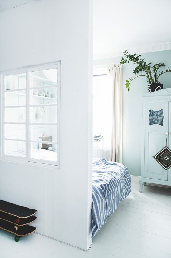 a Scandinavian space in white and pastels shows off an interior window that brings natural light to the entryway