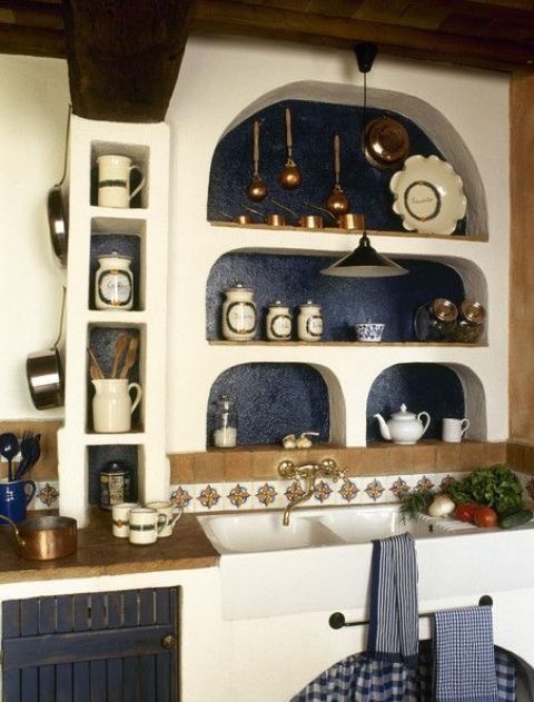 a beautiful vintage Mediterranean kitchen with arched niche shelves, tiles, a large sink and brass items looks wow