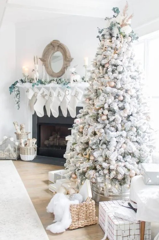 a beautiful winter wonderland Christmas nook with a flocked Christmas tree, silver and gold ornaments, greenery and pampas grass, white stockings and white candles
