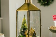 a brass lantern with faux snow, a succulent and bottle brush trees with decor plus a gilded deer is a lovely Christmas terrarium