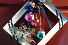 a bright Christmas frame wreath with stripes, a silver pinecone, colorful ornamnets, some bows, ribbons and berries