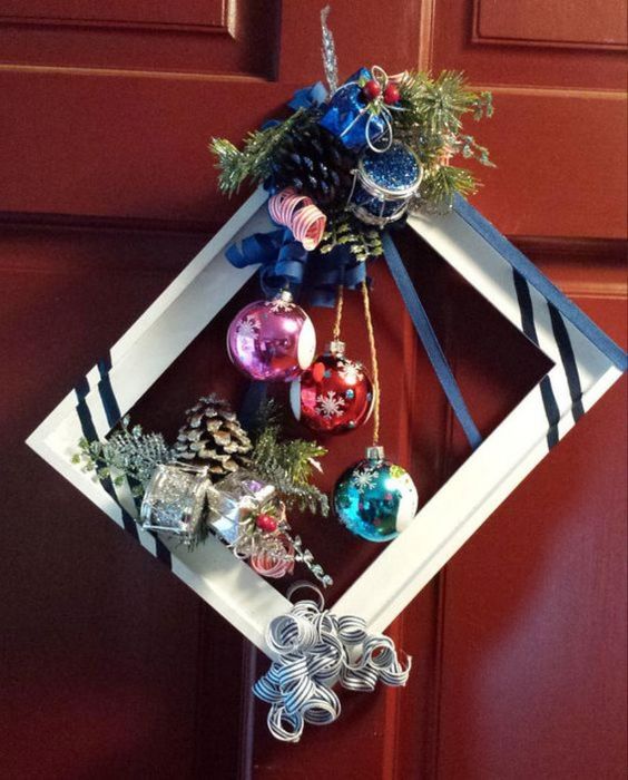 a bright Christmas frame wreath with stripes, a silver pinecone, colorful ornamnets, some bows, ribbons and berries