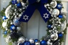 a bright Christmas wreath with bold blue, silver and white oraments and a large navy velvet bow on top is an amazing decoration
