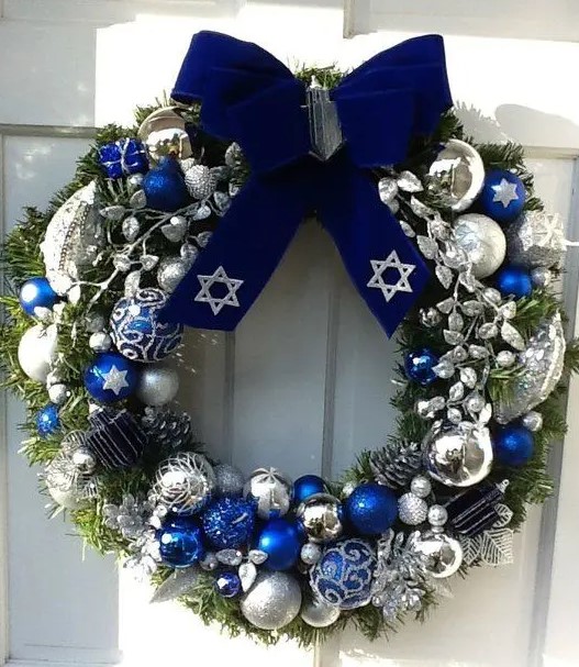a bright Christmas wreath with bold blue, silver and white oraments and a large navy velvet bow on top is an amazing decoration