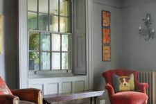 a bright and refined entryway with grey walls, a bright rug and vintage chairs, a bold gallery wall and an interior window