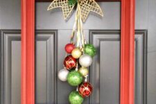 a bright frame Christmas wreath with silver, gold, red and green ornaments, a gold bow with greenery and a pinecone