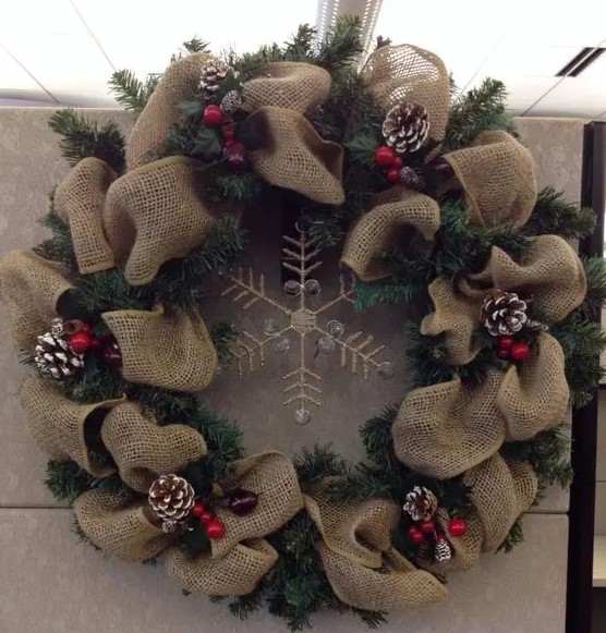 a burlap and evergreen wreath with a rhinestone snowflake, snowy pinecones and cranberries