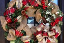 a burlap wreath with plaid and gold ribbon, pinecones, berries and evergreens for a Christmas door