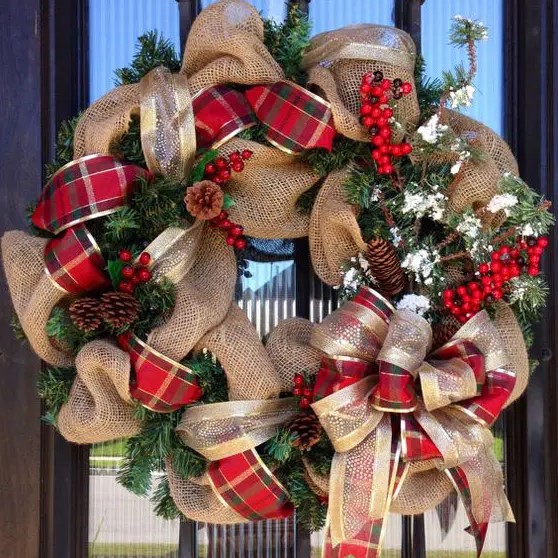 a burlap wreath with plaid and gold ribbon, pinecones, berries and evergreens for a Christmas door
