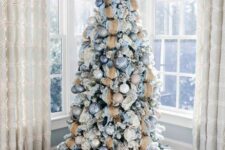 a chic Christmas tree decorated with pastel blue, white, silver and beige ornaments, with matching ribbons and twigs on top