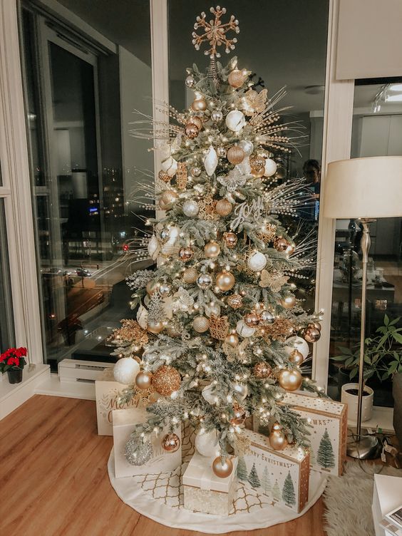 a chic Christmas tree with silver, copper and gold ornaments, greenery, twigs, a gold snowflake on top and some lights