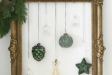 a chic Christmas wreath of a vintage frame, some evergreens, a peacock feather, hanging ornaments is a cool idea