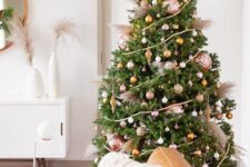 a chic and refined Christmas tree with white, copper, gold and rose gold ornaments of various sizes, wooden beads and pampas grass