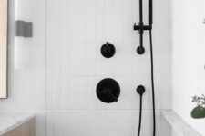 a chic bathroom with white skinny tiles, a niche shelf with black edge for storage, black fixtures