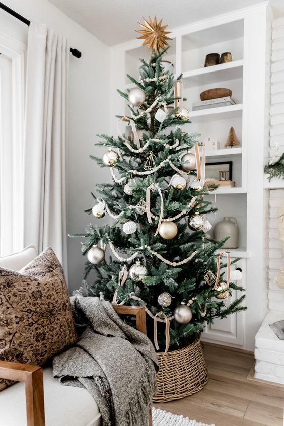 a chic neutral Christmas tree decorated with matte and shiny silver ornaments and gold ones, wooden beads and velvet bows