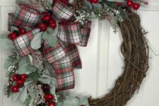 a classic rustic Christmas wreath with greenery, berries, pinecones, twigs and a plaid bow is a stylish and cool decor idea