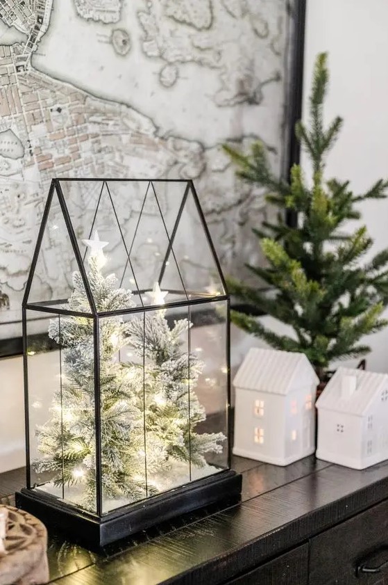 a classy modern Christmas terrarium with flocked mini trees inside and some lights is a very stylish and out of the box idea