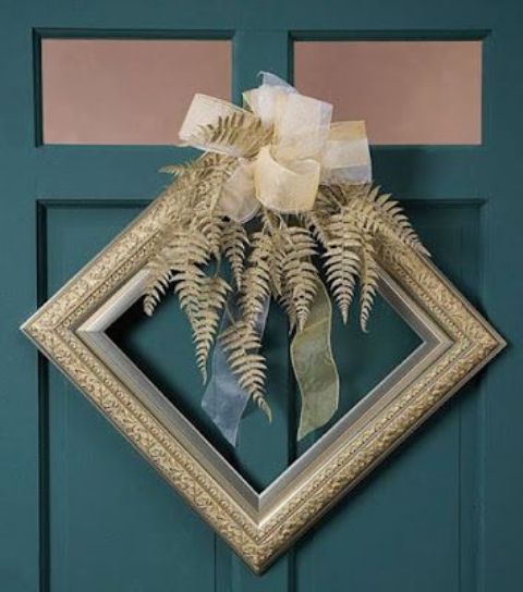 a decorative gold frame Christmas wreath with gilded leaves and a large ribbon bow on top is a fantastic idea for a glam space