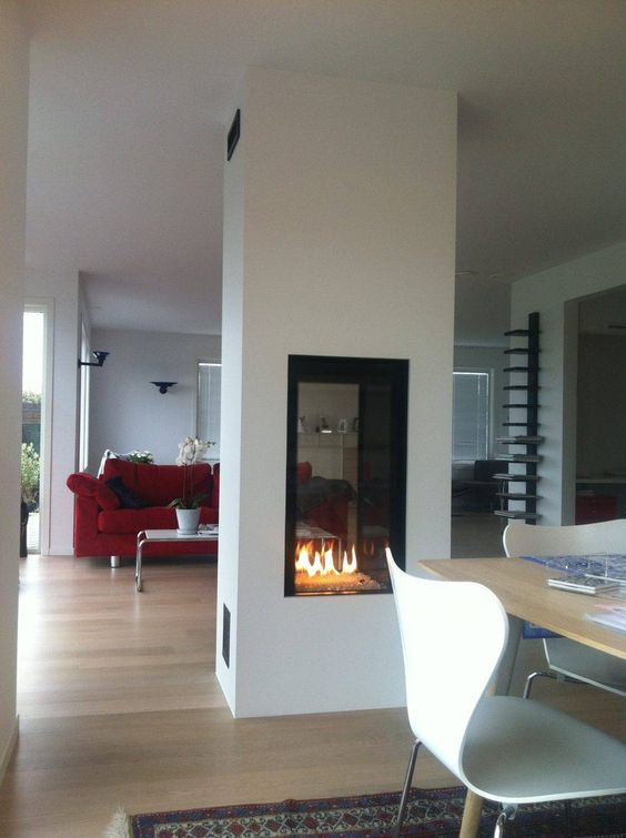 a double-sided white fireplace separating the living room and the dining rooms looks very chic, cozy and cool