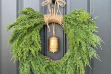 a fantastic juniper and cedar Christmas wreath with a gold hanging bell is a bold solution for a vintage rustic Christmas space
