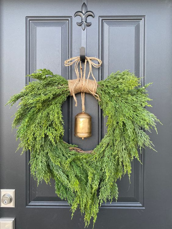 a fantastic juniper and cedar Christmas wreath with a gold hanging bell is a bold solution for a vintage rustic Christmas space