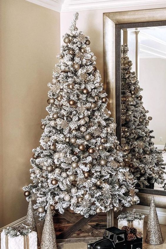 a flocked Christmas tree decorated with white, silver and copper ornaments is a beautiful monochromatic statement