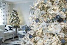 a flocked Christmas tree decorated with white, silver, black, denim and pastel blue ornaments, lights and snowflakes