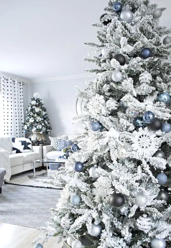 a flocked Christmas tree with blue, silver and black ornaments is a lovely and chic piece that looks frozen and elegant