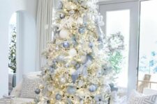 a flocked Christmas tree with lights, silver and blue ribbons and ornaments plus matching bows looks heavenly beautiful