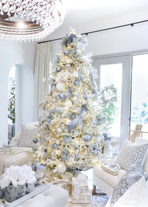 a flocked Christmas tree with lights, silver and blue ribbons and ornaments plus matching bows looks heavenly beautiful