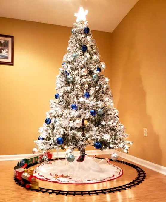 a flocked Christmas tree with lights, silver, navy and light blue ornaments is very beautiful, bold and shiny and looks amazing