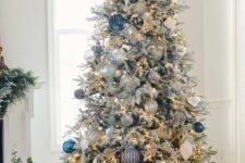 a flocked Christmas tree with lights, white, silver and bold blue ornaments, poinsettias and beads is a gorgeous decoration