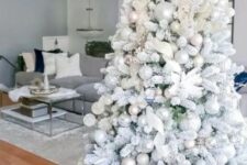 a flocked Christmas tree with metallic ornaments, white fabric ribbons and fabric blooms is a very fairy-tale like idea