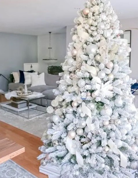 a flocked Christmas tree with metallic ornaments, white fabric ribbons and fabric blooms is a very fairy-tale like idea